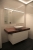 Moderne Badezimmereinrichtung in Krems mit einem eleganten Wandwaschtisch, einem rechteckigen Waschbecken und einem großen Spiegel mit integrierter Beleuchtung.