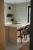 Moderne Küchenecke mit minimalistischem Design, einer Marmorinsel, eleganten schwarzen Hockern und eleganter Pendelleuchte, gebadet in natürlichem Sonnenlicht.