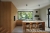 Eine moderne Küche mit eleganten Holzoberflächen, die durch große Fenster durch natürliches Licht beleuchtet wird, mit einer zentralen Insel mit Barhockern in einem Haus in der Steiermark.