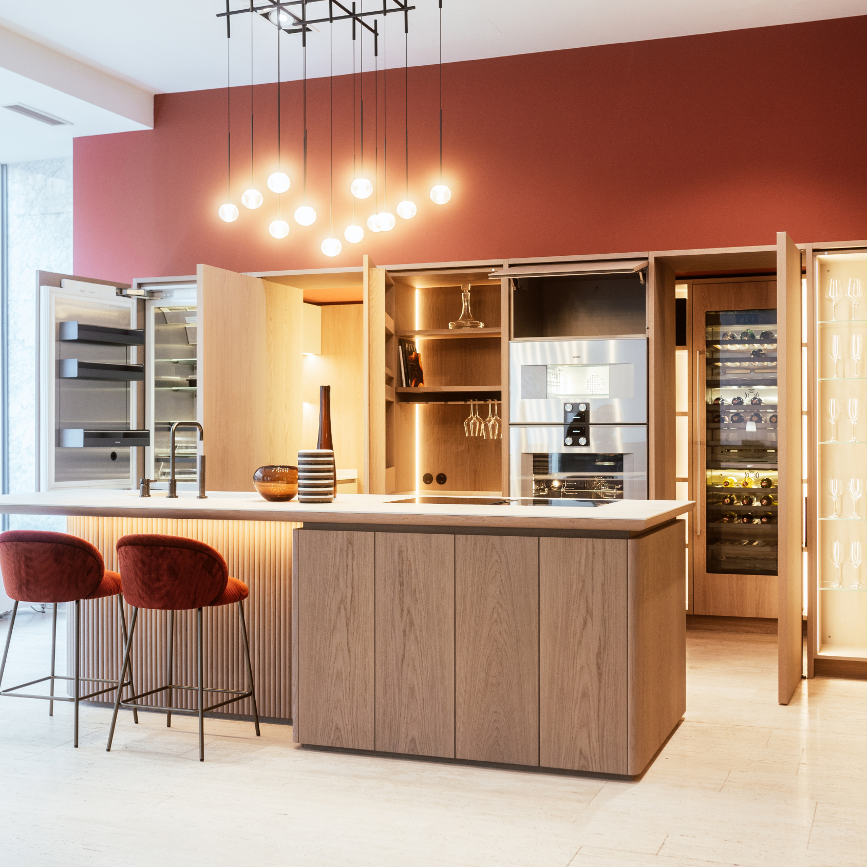 Moderne Küche mit eleganter Kochinsel, Terrakottawänden und modernen Geräten, ergänzt durch stilvolle Pendelleuchten und gemütliche Barhocker.