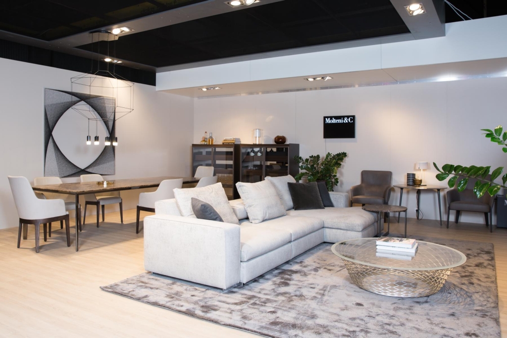 Elegante und moderne Wohnzimmerpräsentation in einem Ausstellungsraum mit einem weichen Sofa, einer modernen Essgruppe und geschmackvollen Dekorakzenten.