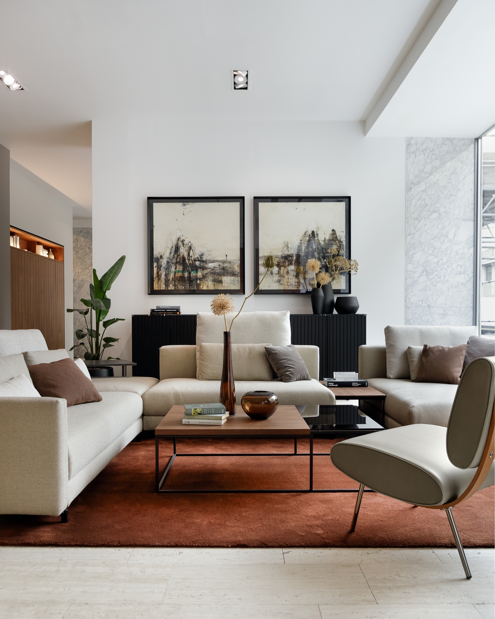 Moderne Wohnzimmereinrichtung mit einem raffinierten neutralen Farbschema, bestehend aus einem weichen Sofagarnitur, einem eleganten Sessel und einem eleganten Couchtisch, ergänzt durch abstrakte Wandkunst und dezente Dekorakzente.